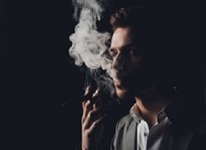 Handsome man in suit on the black background smoking a cigar