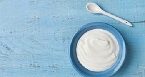 Yoghurt intake associated with lowered risk of cardiovascular disease Greek yogurt in blue bowl on rustic wooden table top view.
