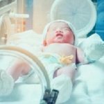 Newborn baby girl inside incubator in hospital post delivery room