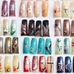 Artificial acrylic nails painted in various designs on display in nail salon
