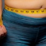 Woman in Active Wear With Squeezed Measuring Tape on a Gray Background