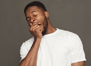 Black man yawning on grey background, studio shot, copy space