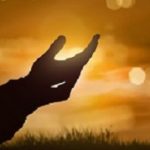 Silhouette of human hand with open palm praying to god at sunset background