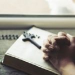 woman hand cross on the book in window background