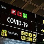 Information panel with Covid-19 word on it at an international airport.