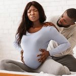 Pregnant lady suffering from backache, husband massaging her shoulders