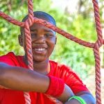 Portrait of happy boy leaning on net during obstacle course