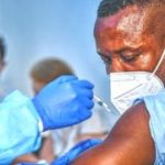 african americam man looking at coronavirus covid-19 syring when medical staff injecting vaccine to arm muscle to build immunization of coronavirus covid-19 for him