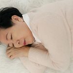 Asian senior woman wear pink sweater sleep on fur bed