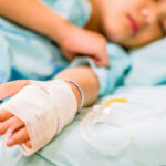 Closeup kid hand  sleeps on a bed in hospital with saline intravenous.