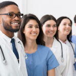 Team of doctors and interns standing in hospital in row and looking aside