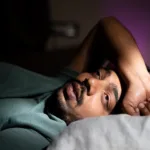young man unable to sleep during night at bedroom – concept of suffering from insomnia, thoughtful and problems