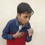 Boy covered mouth with hand, cough, keeping hand on chest