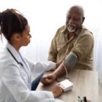 Black female doctor checking measuring pressure on patient's hand