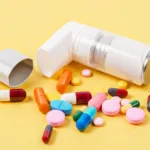 White asthma inhaler and colorful pills drug